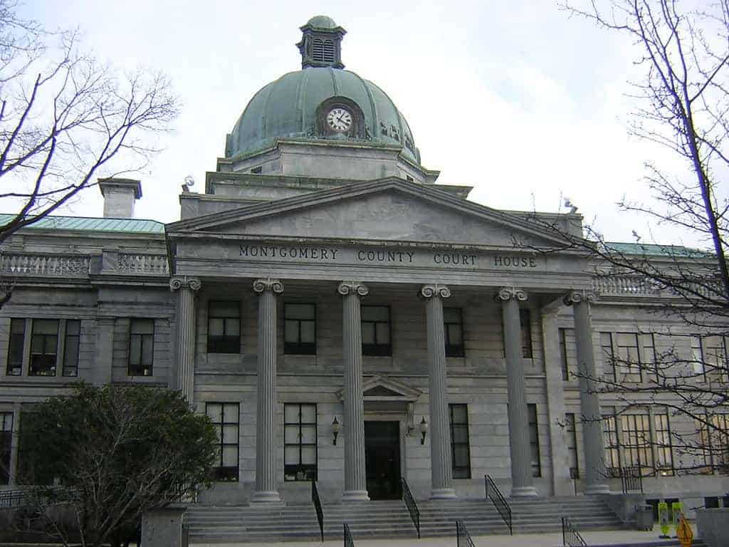 Front view of Montgomery County Courthouse with four columns, a dome on top, and "Montgomery County Court House" inscribed on the facade.