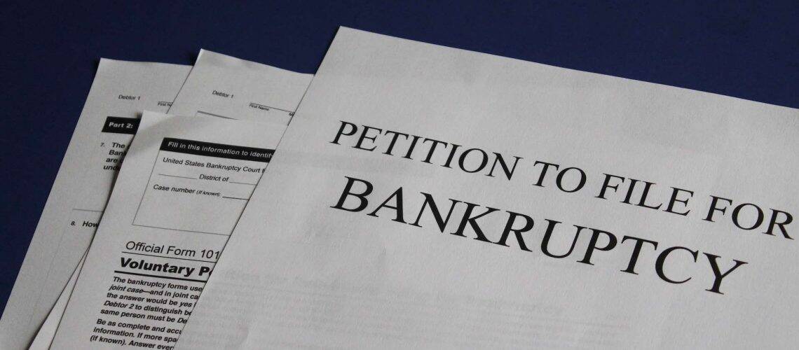 Documents labeled "Petition to File for Bankruptcy" on a blue surface.