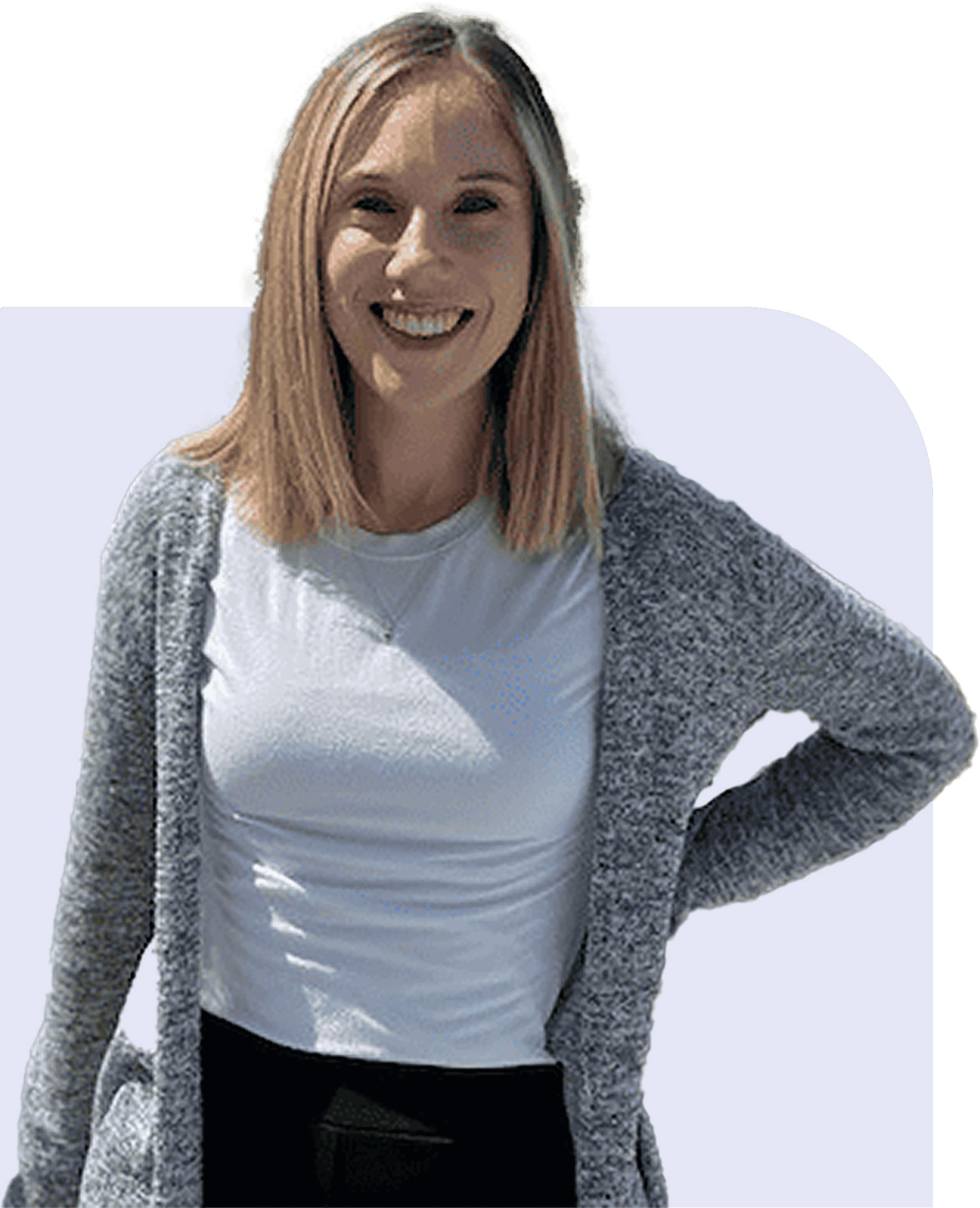 Smiling woman with straight blonde hair, wearing a gray cardigan over a white shirt, stands with one hand on her hip against a light background.
