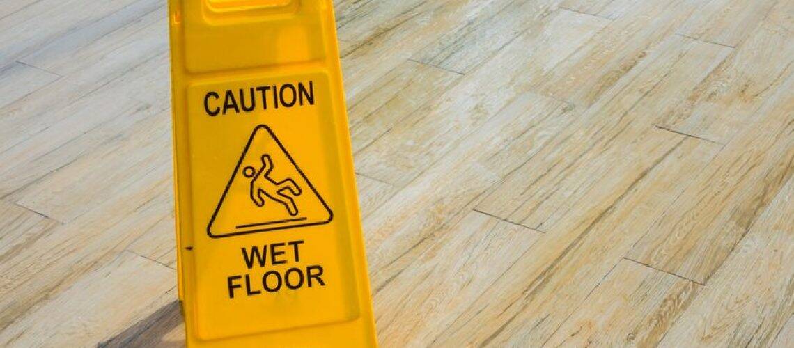 Yellow "Caution Wet Floor" sign on wooden floor.