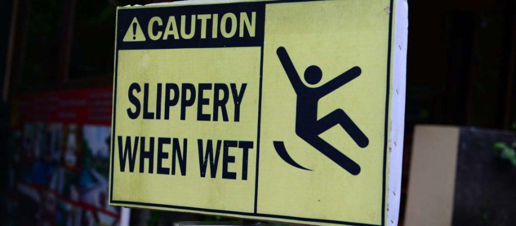 Yellow caution sign reading "Slippery When Wet" with a symbol of a person slipping.