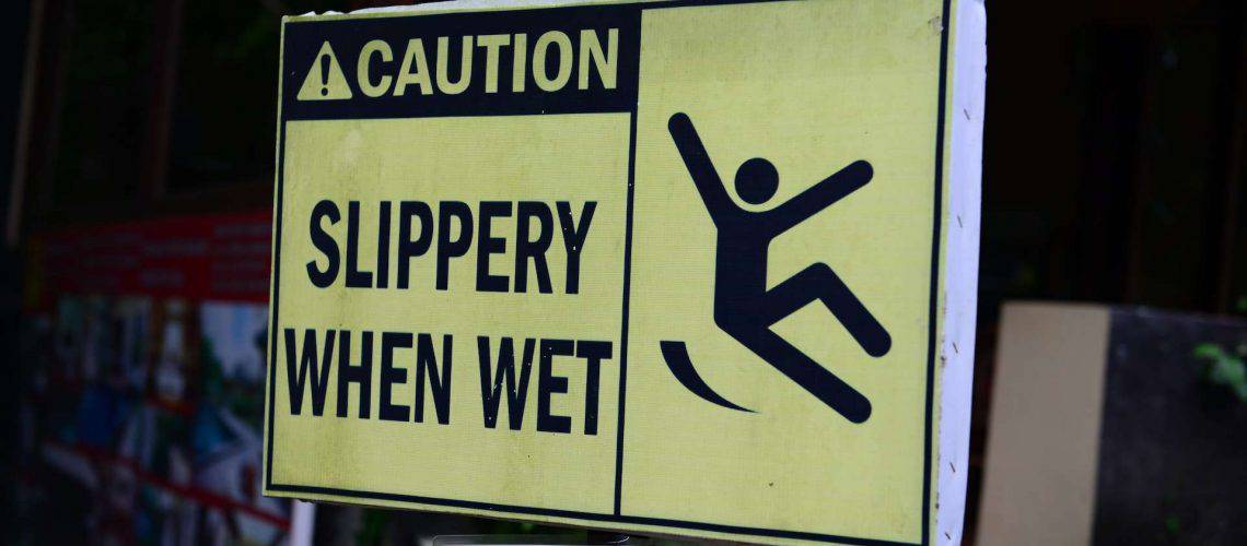 Yellow caution sign reading "Slippery When Wet" with a symbol of a person slipping.